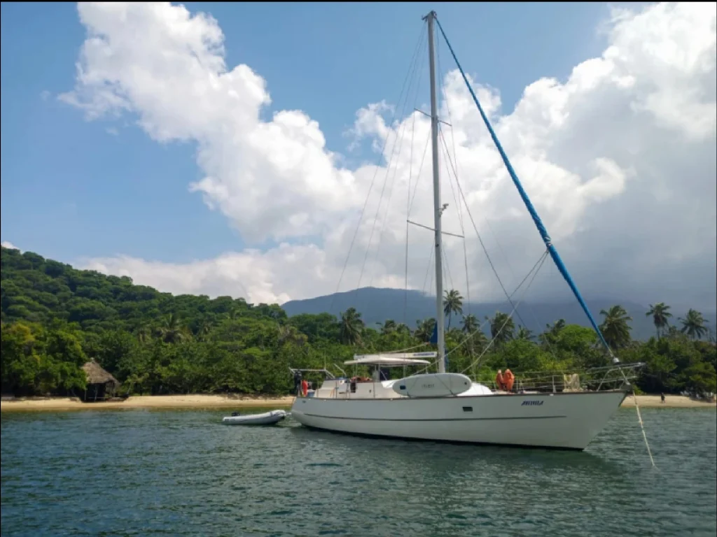 Velero anclado en la bahía del Parque Tayrona con montañas al fondo.
